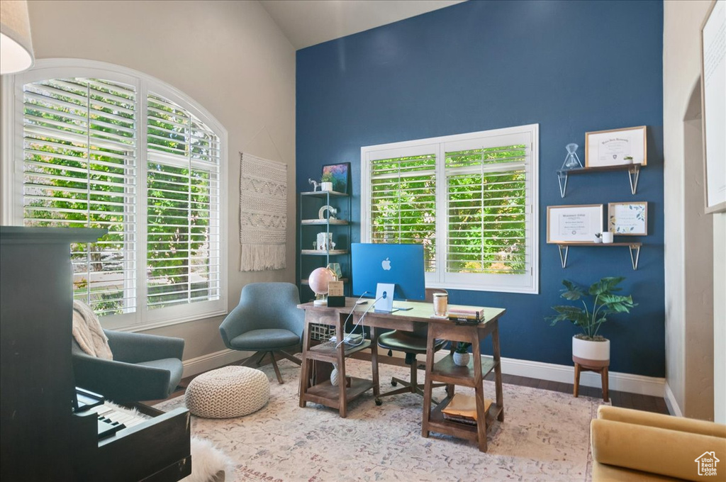 Home office featuring baseboards, high vaulted ceiling, and wood finished floors