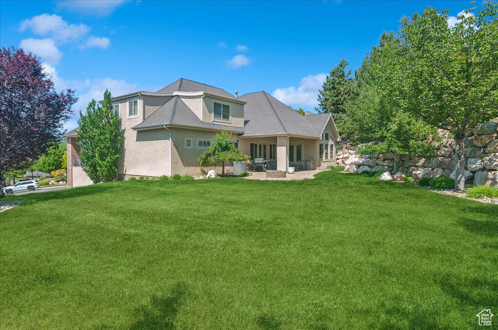 Rear view of property featuring stucco siding and a lawn