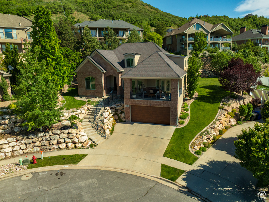View of front of house with brick siding, stairs, driveway, an attached garage, and a front yard