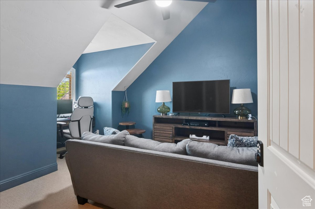 Living room with carpet, ceiling fan, vaulted ceiling, baseboards, and a desk