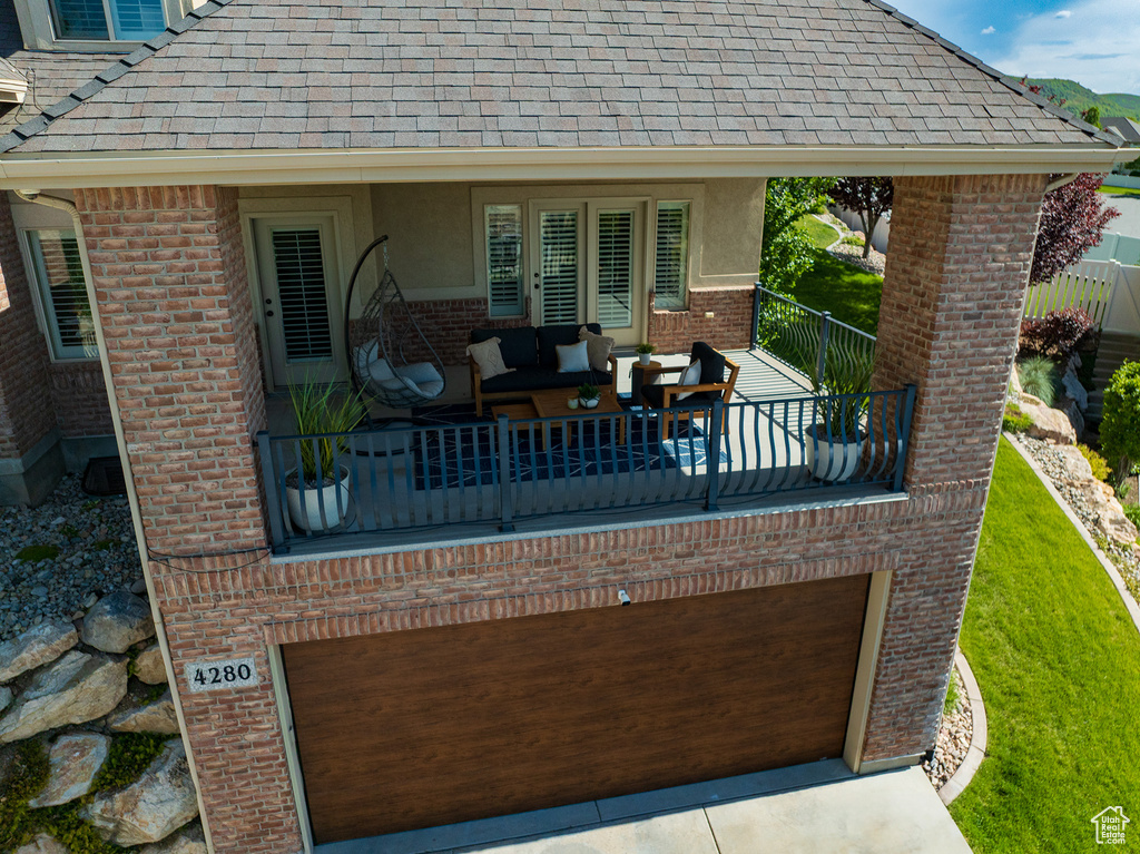 View of patio / terrace with a balcony, an attached garage, and driveway
