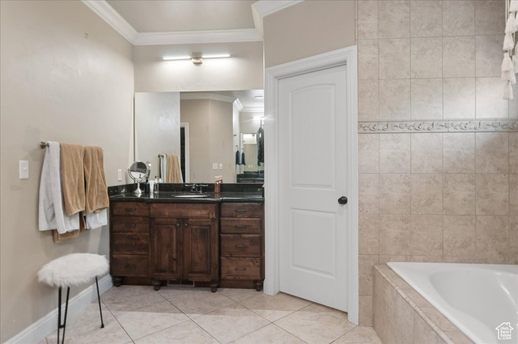Full bath with crown molding, tiled bath, vanity, tile patterned flooring, and baseboards