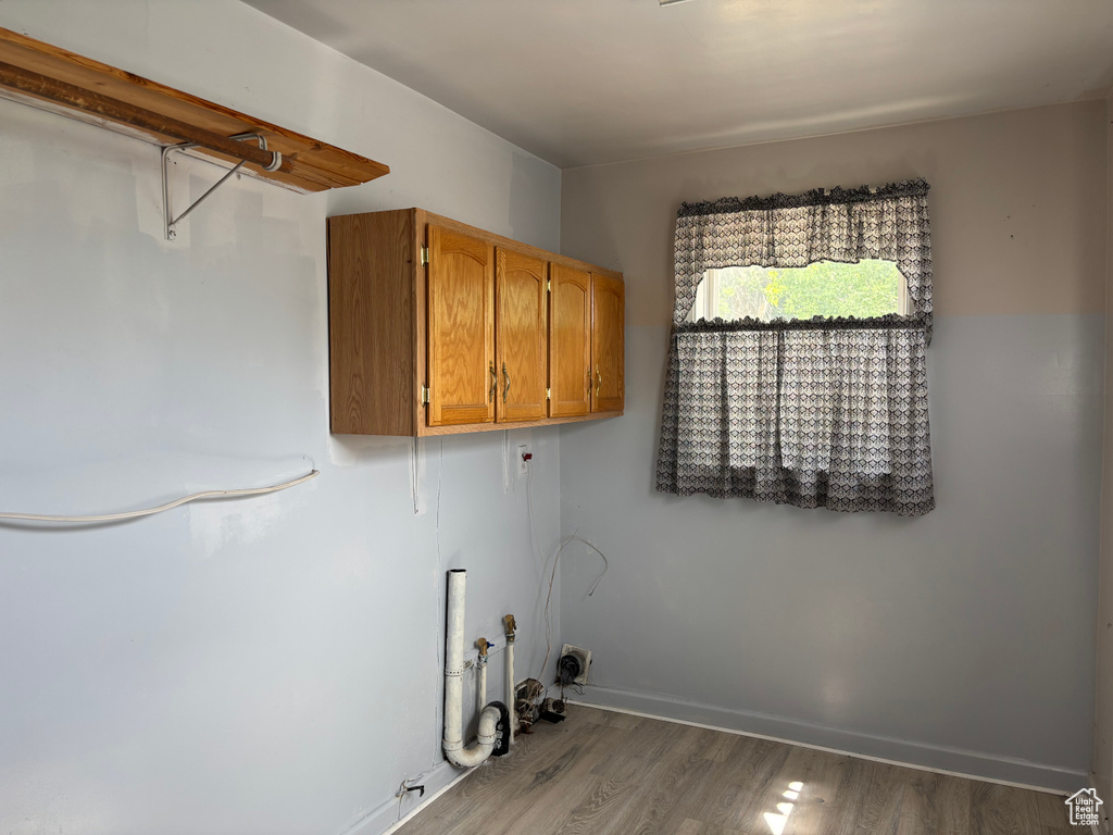 Laundry area with cabinet space, wood finished floors, and washer hookup