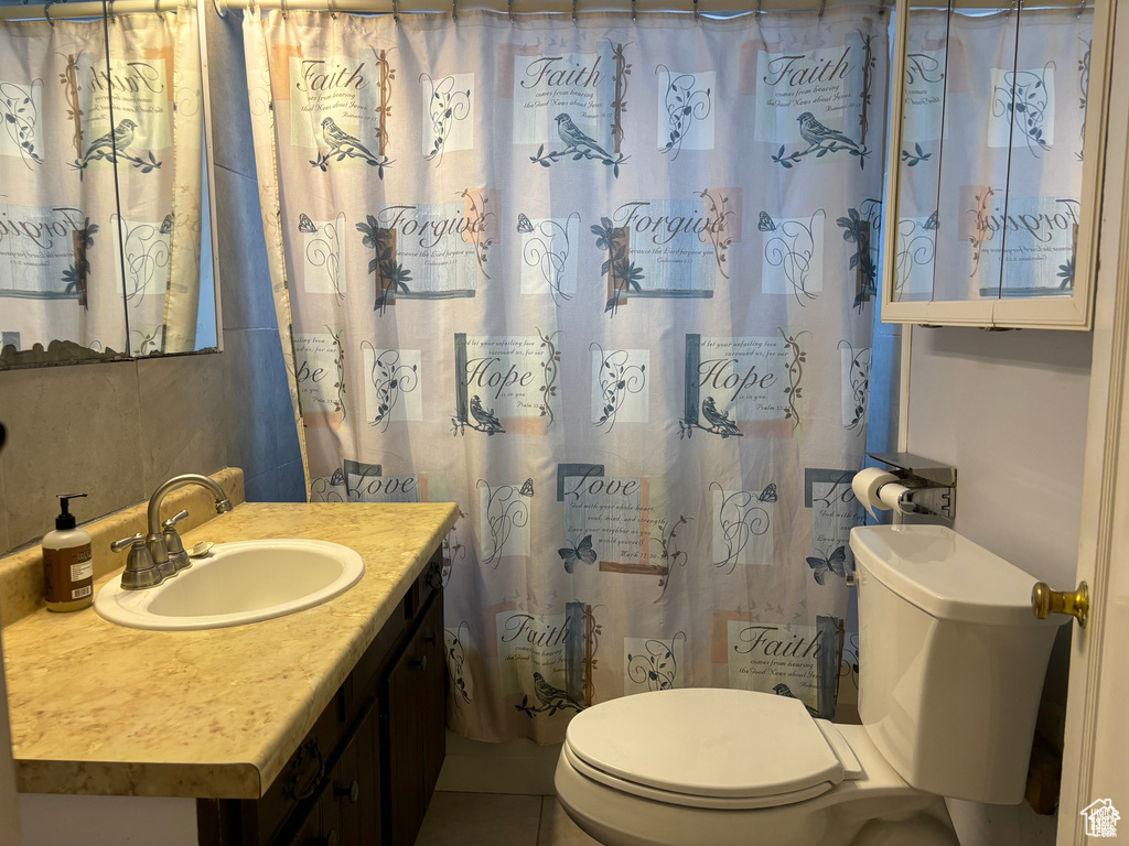 Bathroom featuring toilet, vanity, and curtained shower