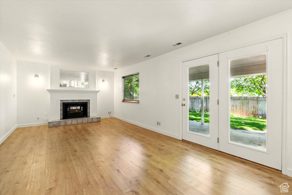 Unfurnished living room featuring light wood-style flooring, a fireplace, and baseboards