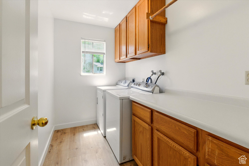 Laundry room featuring cabinet space, light wood-style flooring, independent washer and dryer, and baseboards