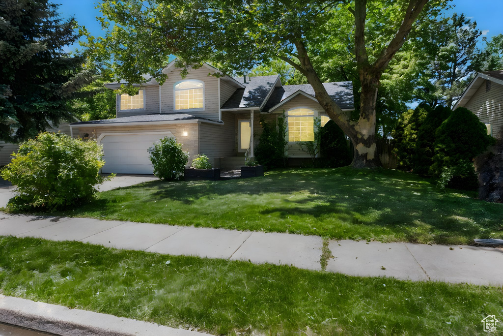 View of front of house with a garage, a front yard, and driveway