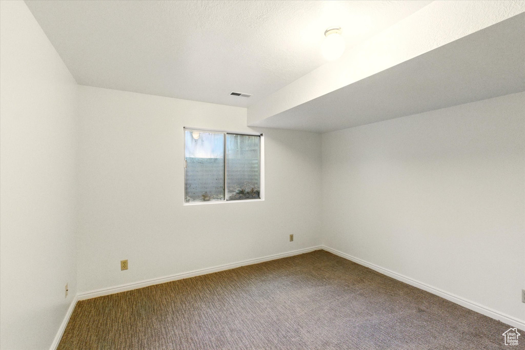Carpeted spare room featuring baseboards
