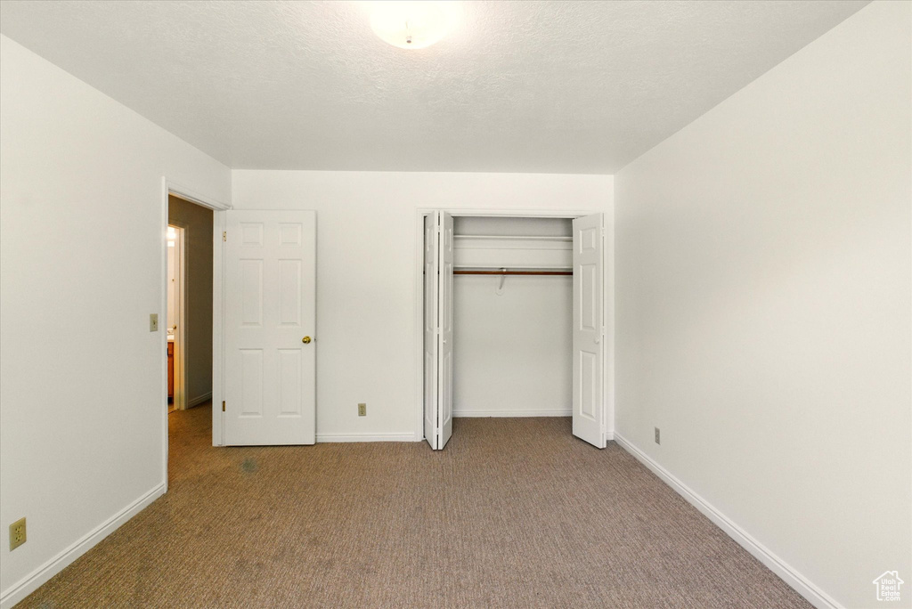 Unfurnished bedroom featuring carpet floors, baseboards, and a closet
