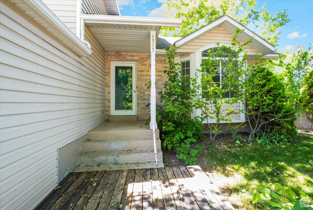 Doorway to property featuring brick siding and a wooden deck
