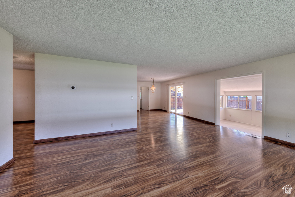 Unfurnished room featuring dark wood-style floors, a textured ceiling, and baseboards