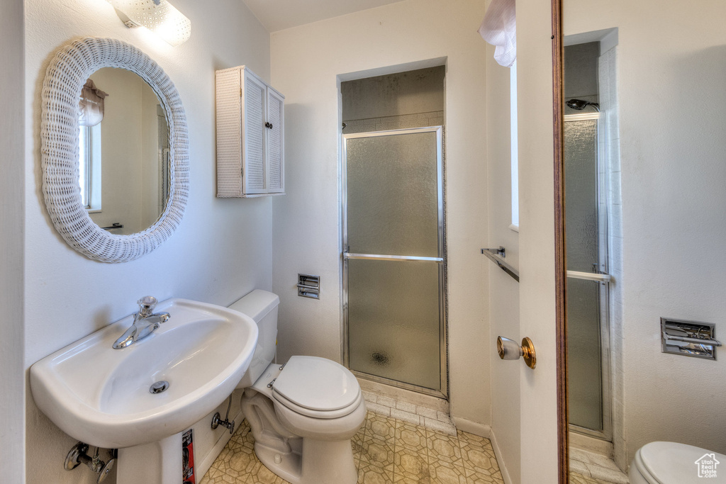 Full bath featuring toilet, a shower stall, and a sink