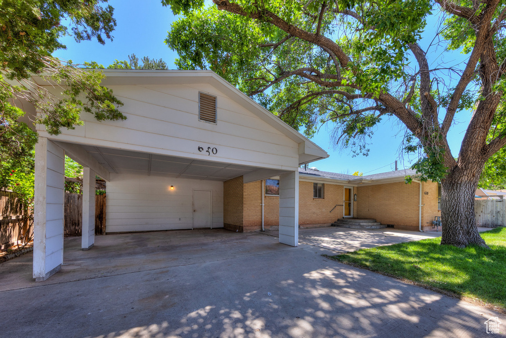 View of front of home with brick siding, a carport, and concrete driveway
