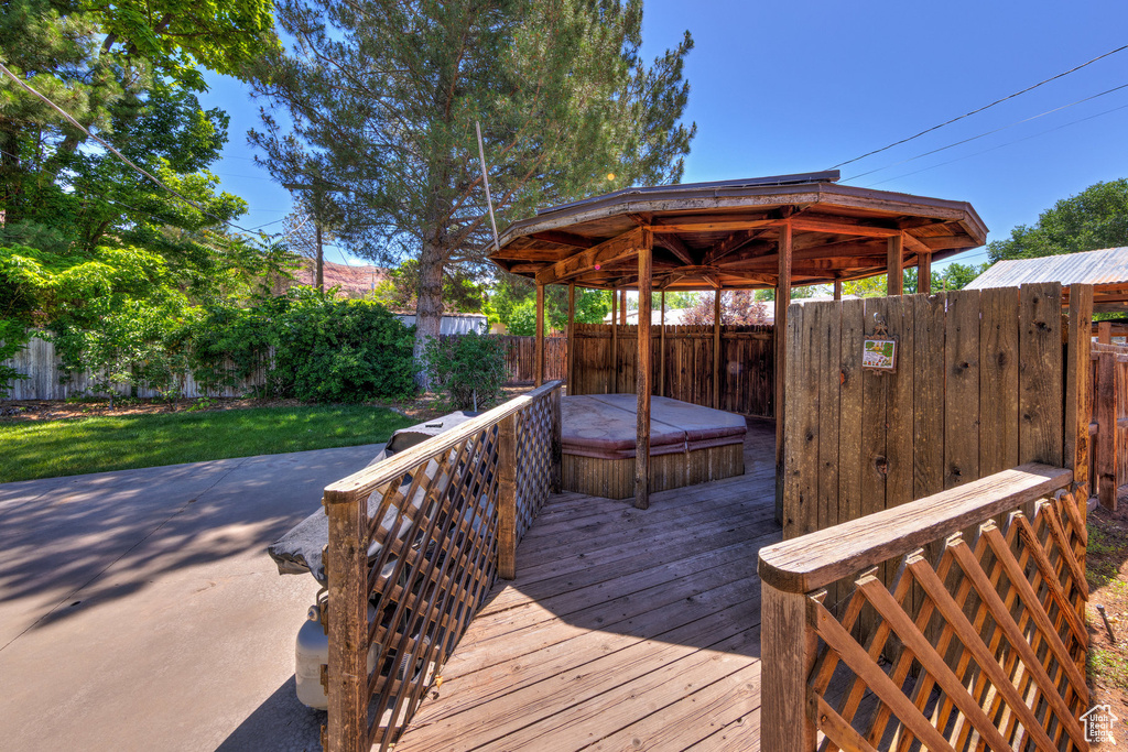 Deck with a gazebo, a covered hot tub, and a fenced backyard