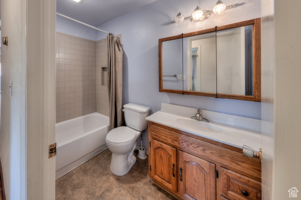 Bathroom with vanity, shower / tub combo, and toilet