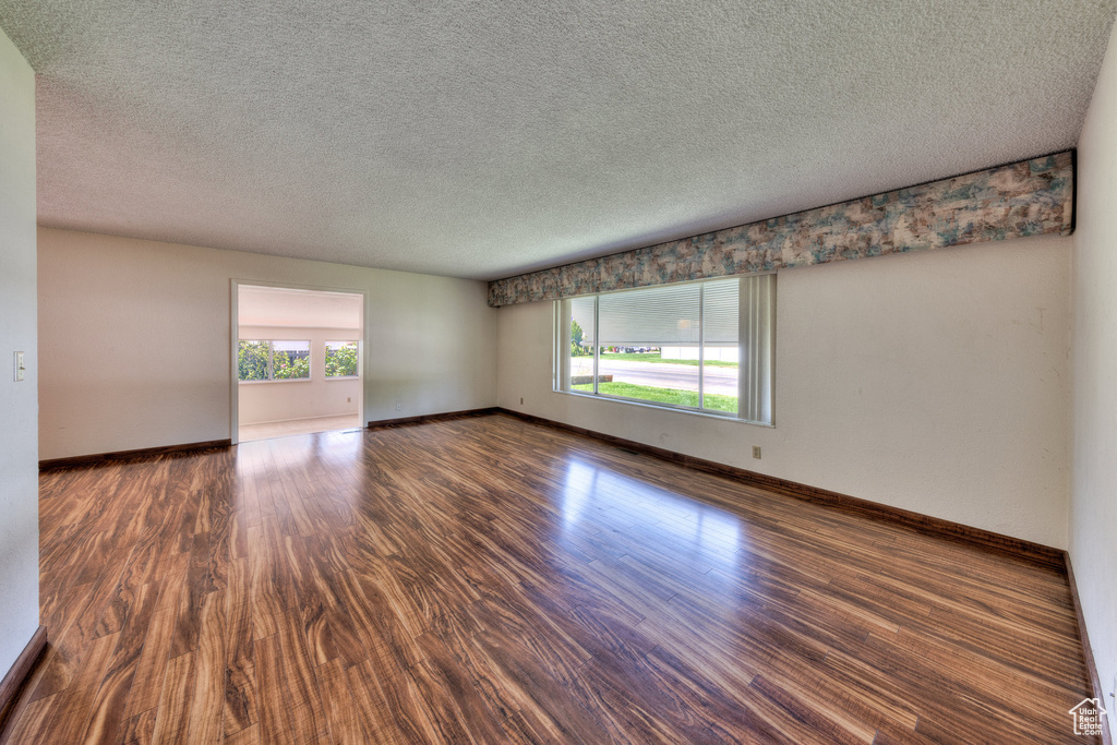 Spare room with plenty of natural light, wood finished floors, a textured ceiling, and baseboards