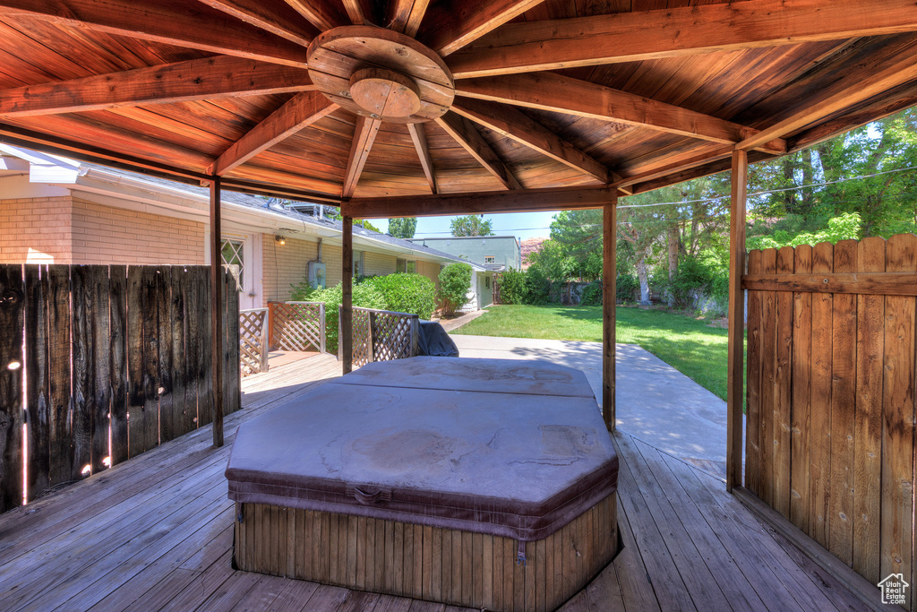 Wooden terrace featuring a covered hot tub and a gazebo