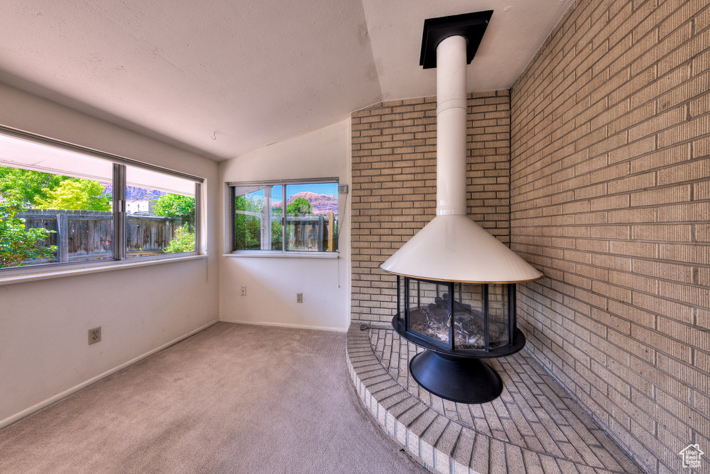 Unfurnished sunroom featuring a wood stove and vaulted ceiling