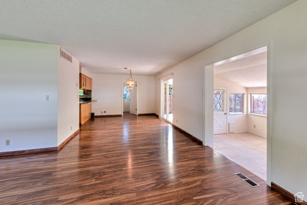 Unfurnished living room featuring dark wood finished floors, a textured ceiling, and baseboards