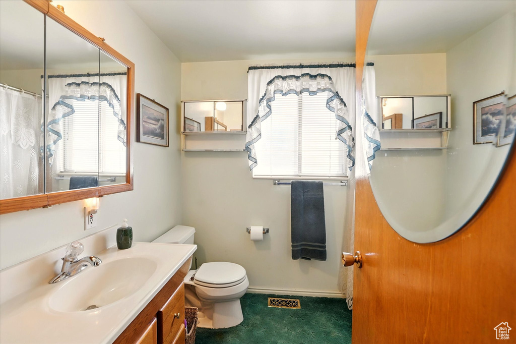 Bathroom featuring healthy amount of natural light, toilet, vanity, and baseboards