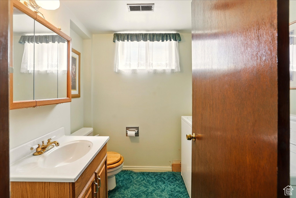Bathroom featuring toilet, vanity, and baseboards