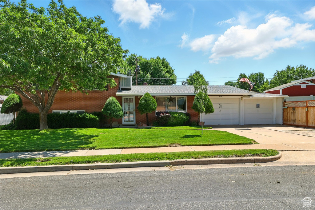 Tri-level home with an attached garage, concrete driveway, and brick siding