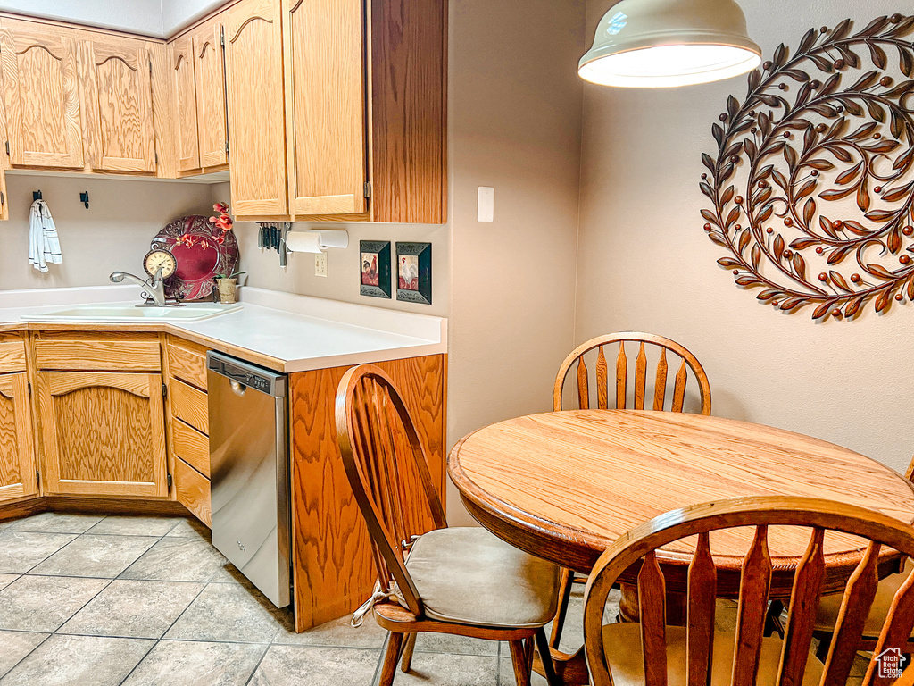 Kitchen with stainless steel dishwasher, a sink, light countertops, and light tile patterned flooring