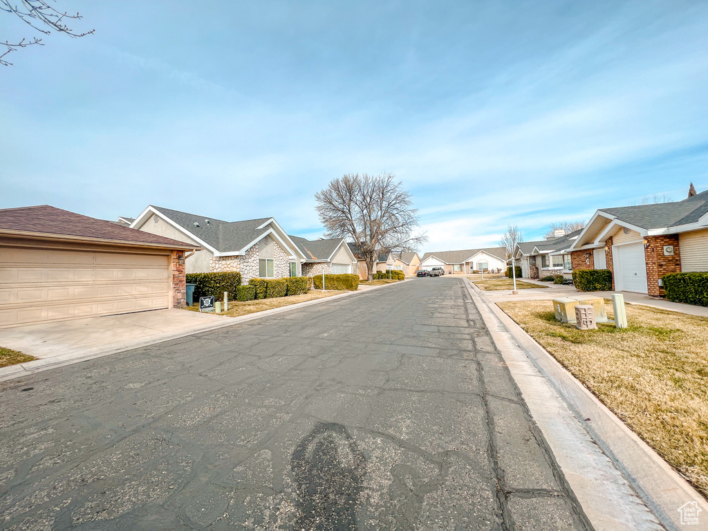 View of asphalt road with a residential view and curbs