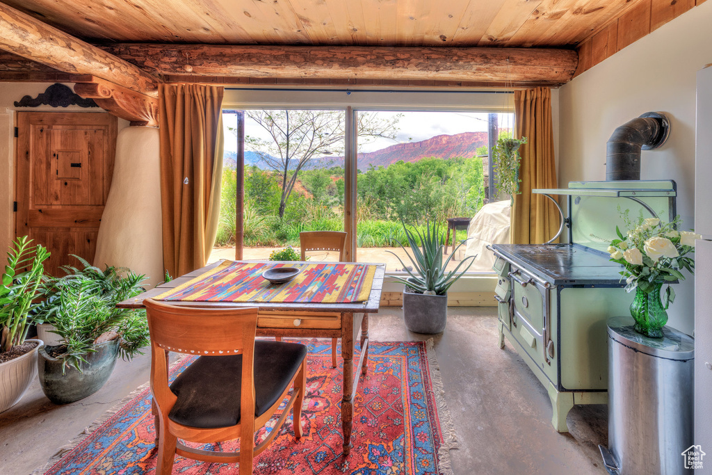Dining space with unfinished concrete flooring, wooden ceiling, a wood stove, and a mountain view