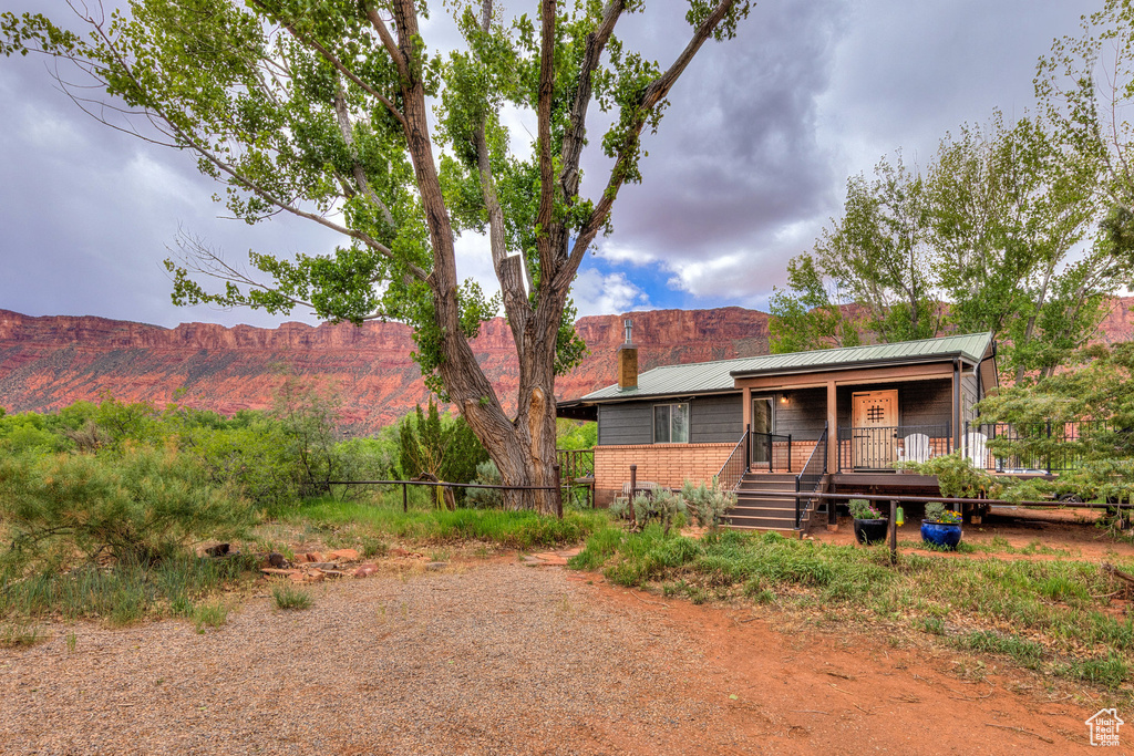 Back of property featuring a chimney, a mountain view, a porch, and metal roof