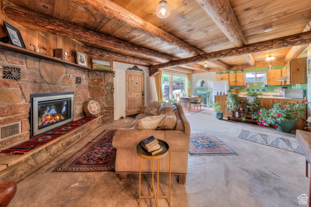 Living area with wood ceiling with exposed beams, unfinished concrete floors, plenty of natural light, and a fireplace
