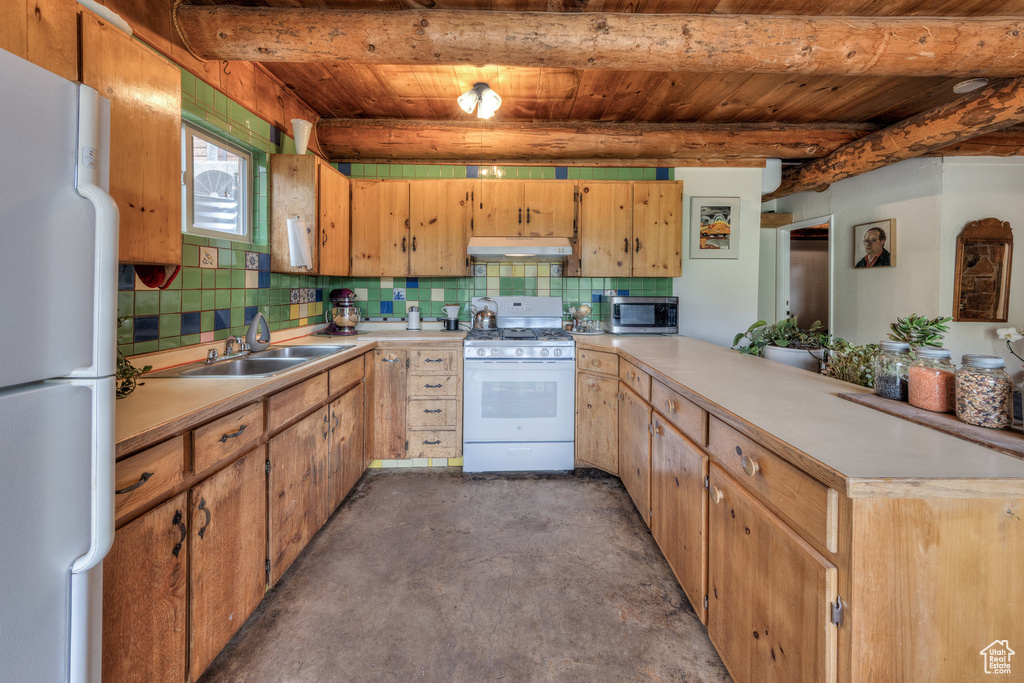 Kitchen featuring white appliances, under cabinet range hood, a sink, a peninsula, and wooden ceiling with exposed beams