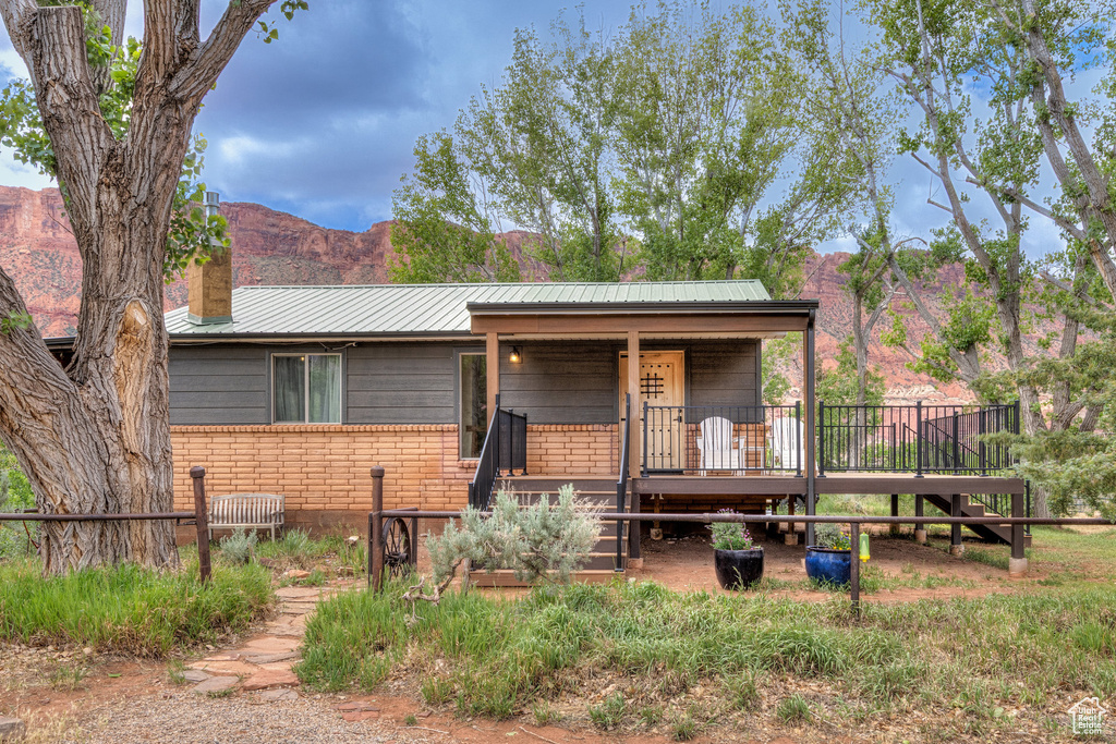 View of front of home featuring a chimney, metal roof, a mountain view, and a porch