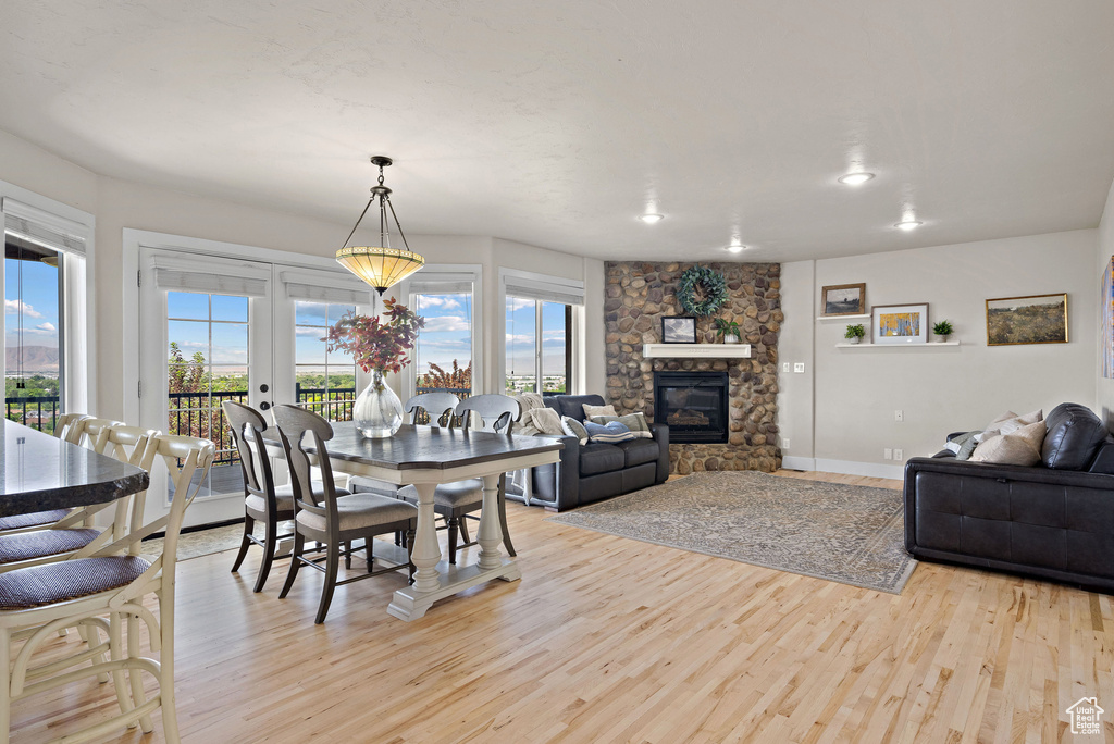 Dining space featuring light wood-style flooring, healthy amount of natural light, a stone fireplace, and baseboards
