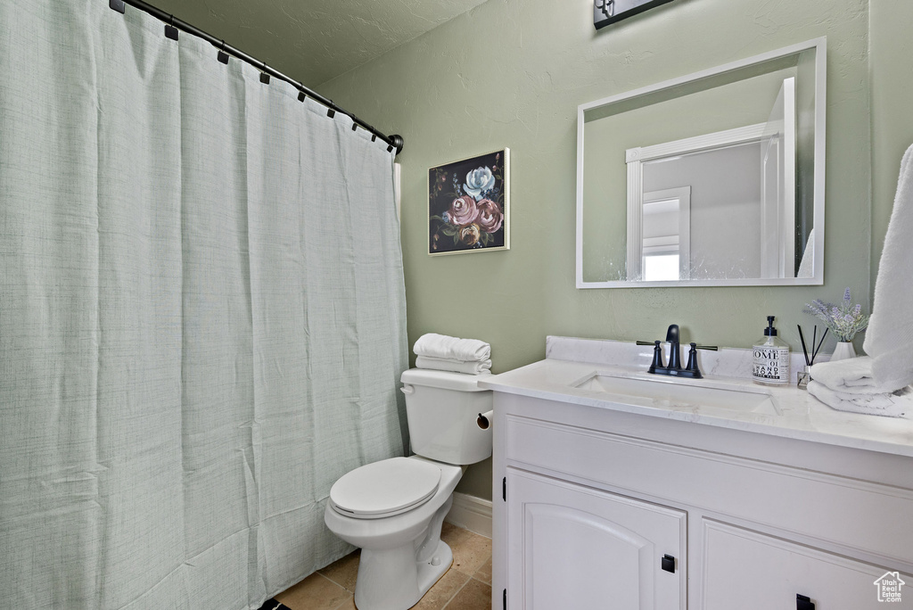 Full bathroom with toilet, vanity, tile patterned flooring, and curtained shower