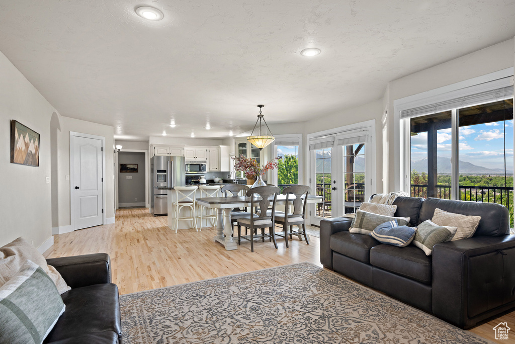 Living area with a mountain view, recessed lighting, light wood-style floors, baseboards, and french doors