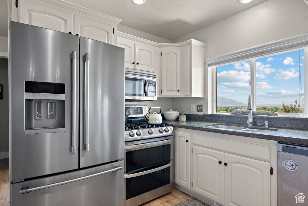 Kitchen featuring stainless steel appliances, a sink, light wood-type flooring, white cabinetry, and recessed lighting