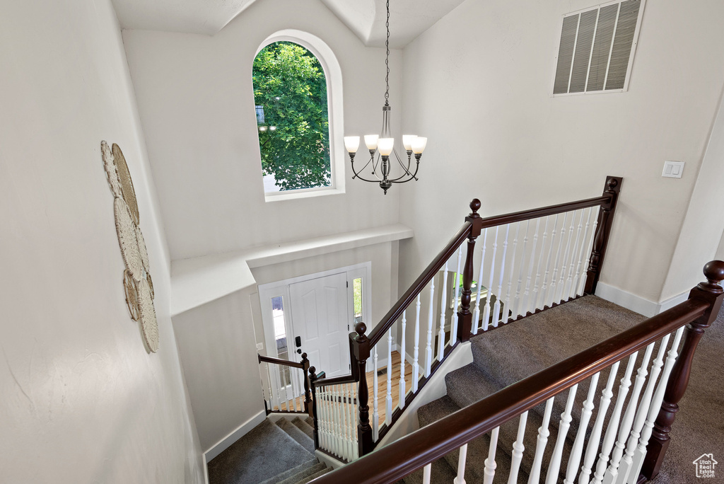 Stairway featuring carpet floors, a chandelier, baseboards, and a towering ceiling