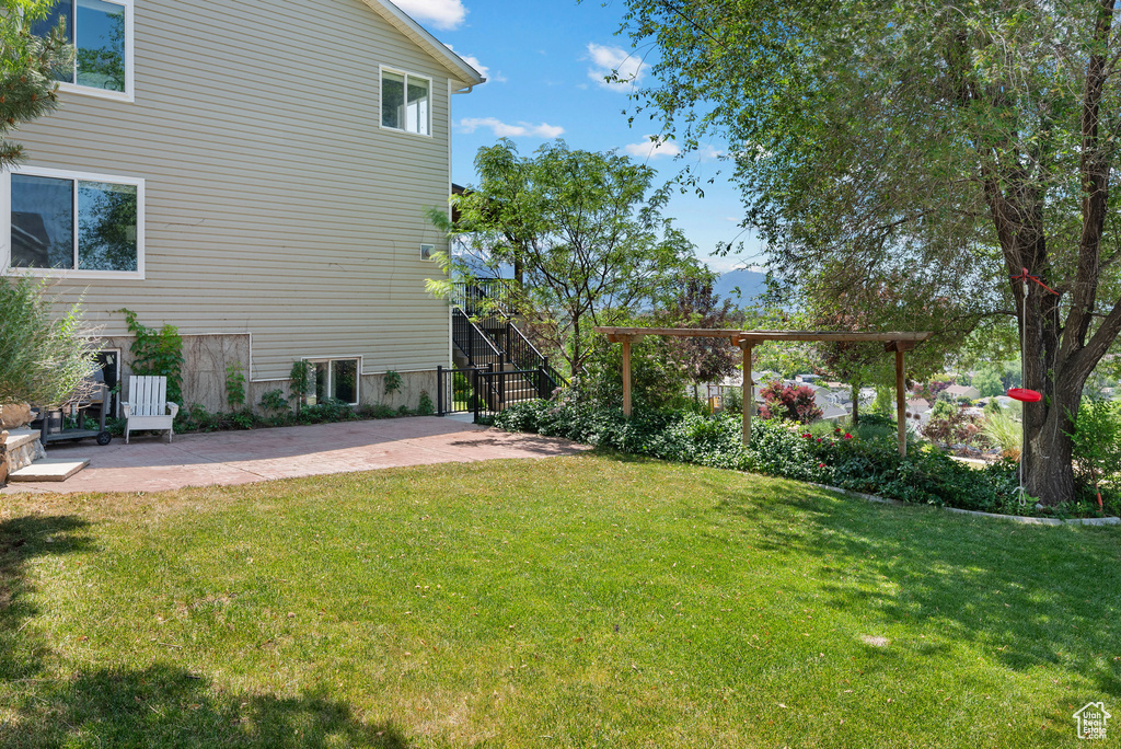 View of green lawn with a patio area