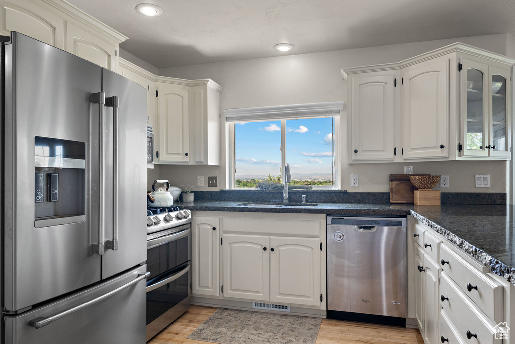 Kitchen featuring stainless steel appliances, a sink, recessed lighting, white cabinets, and light wood-style flooring