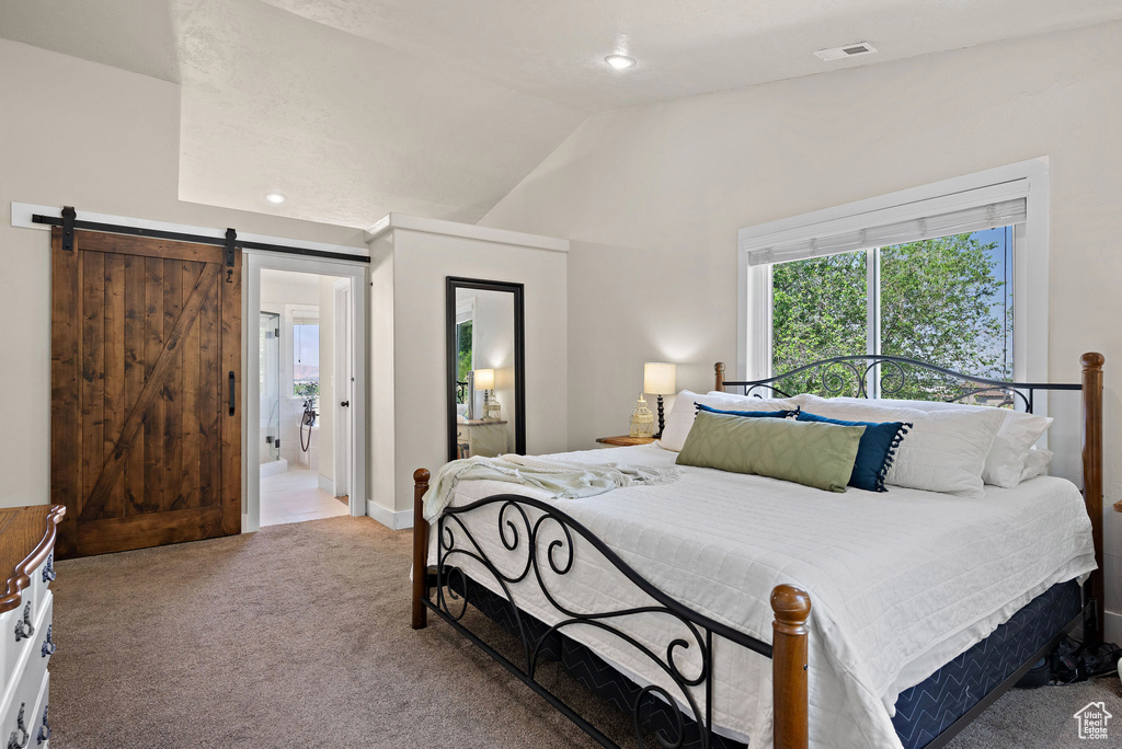Carpeted bedroom with lofted ceiling, a barn door, and baseboards