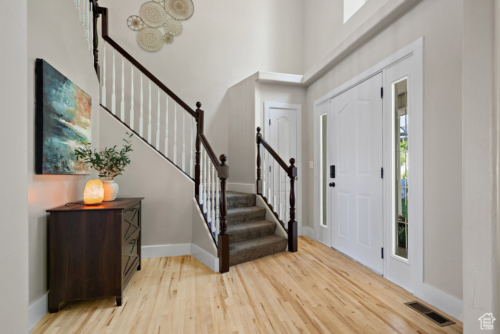 Entrance foyer featuring light wood-style floors, baseboards, stairway, and a towering ceiling