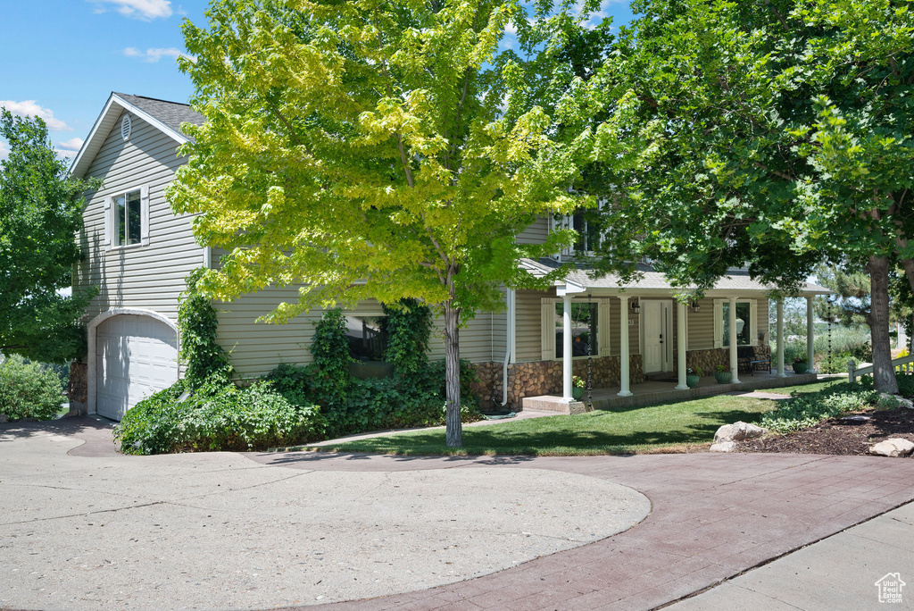 Obstructed view of property with a porch, a garage, and stone siding