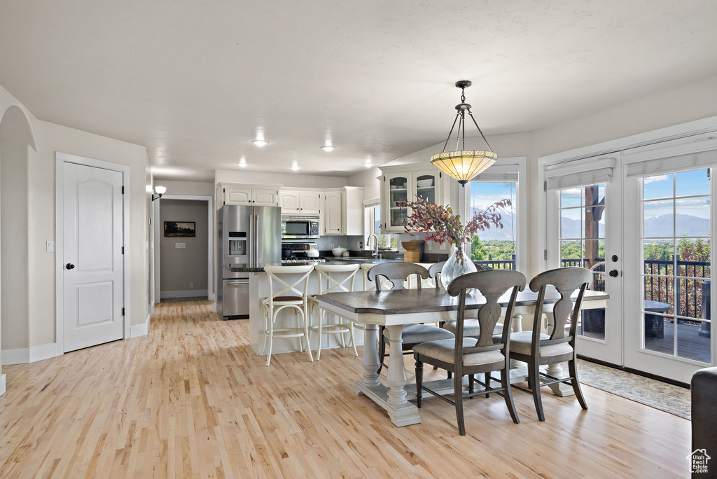 Dining area featuring light wood-style flooring, baseboards, french doors, a mountain view, and arched walkways