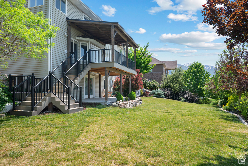 View of green lawn featuring stairs and a patio area