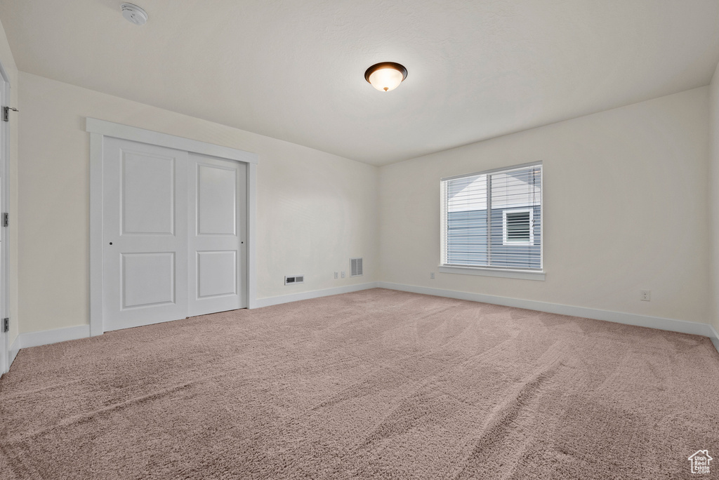 Unfurnished bedroom featuring light colored carpet and baseboards