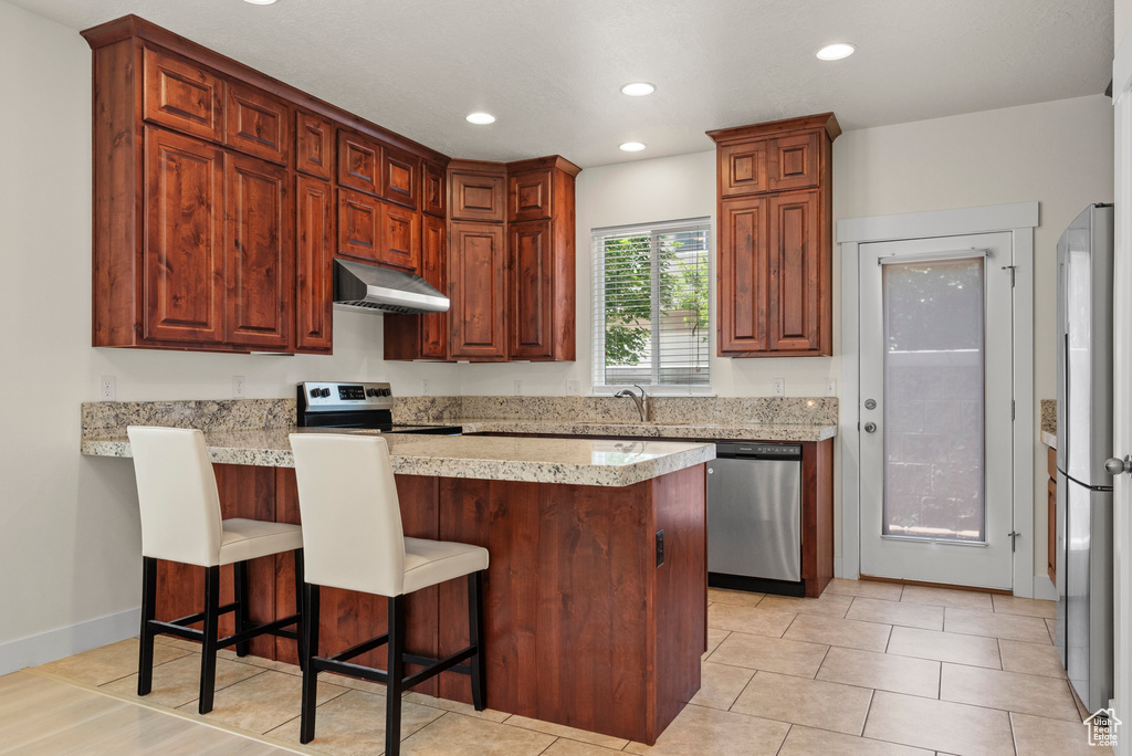 Kitchen with stainless steel appliances, extractor fan, a peninsula, a kitchen breakfast bar, and recessed lighting