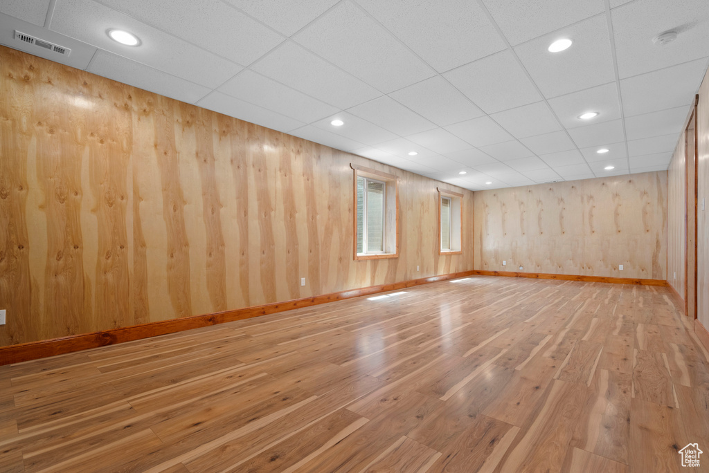 Empty room with wood finished floors, baseboards, recessed lighting, and wooden walls