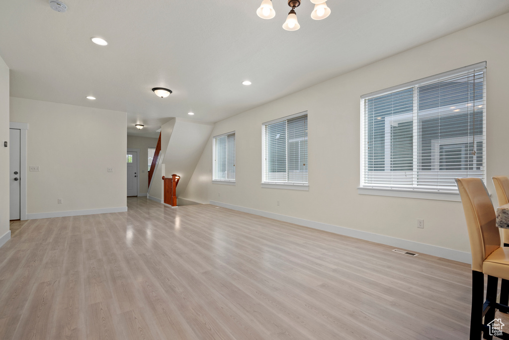 Unfurnished living room with light wood-style flooring, baseboards, recessed lighting, and a chandelier