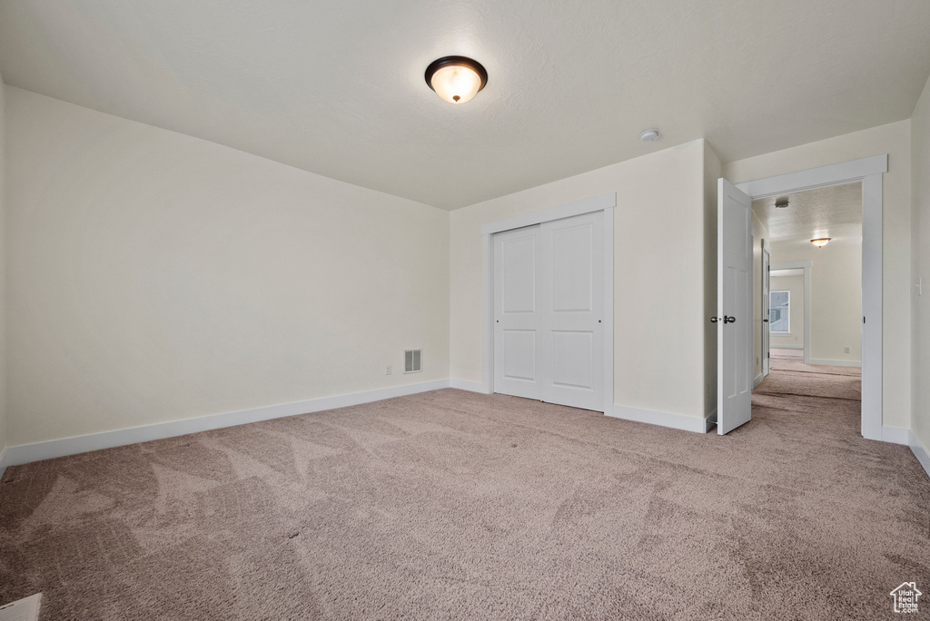 Unfurnished bedroom with carpet floors, baseboards, and a closet